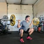 man lifting barbell on back inside gym